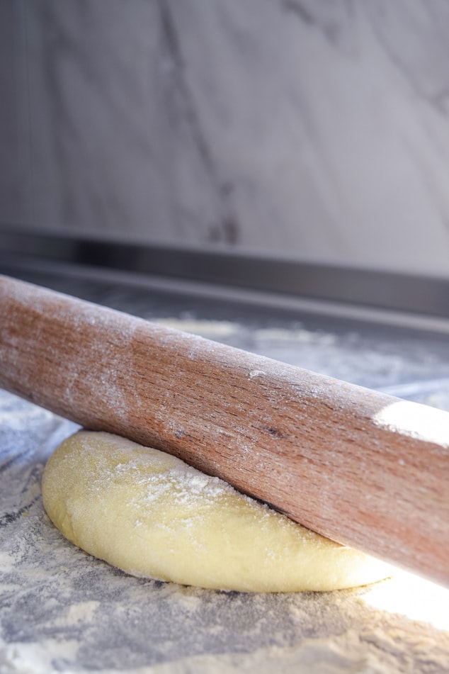 Rolling out bread dough with flour and a rolling pin,