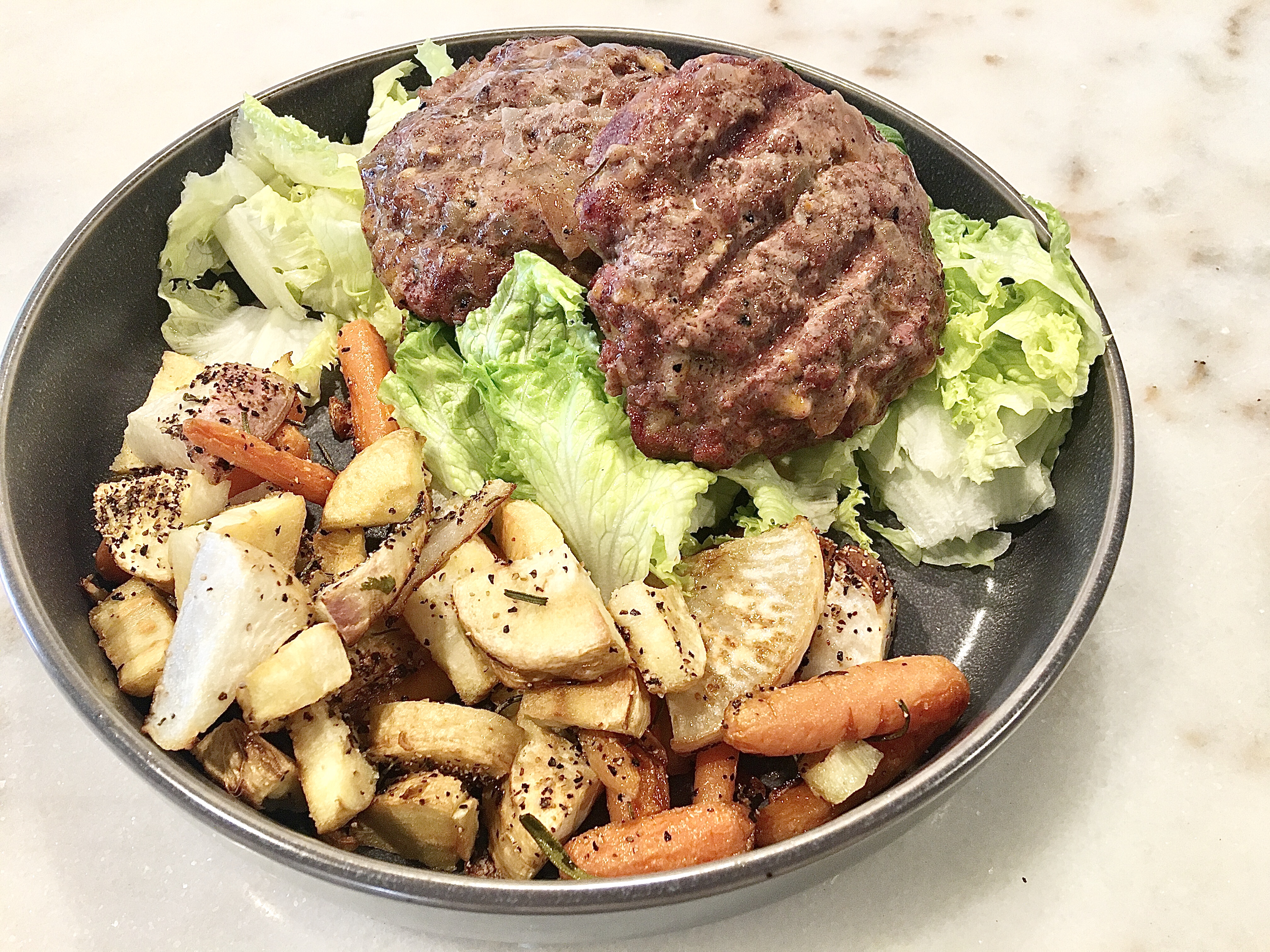 winter root vegetables full of parsnips, turnips, and carrots with a juicy hamburger on a bed of lettuce keto style