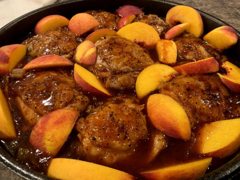 Barbeque peach chicken in a black cast-iron skillet. 
