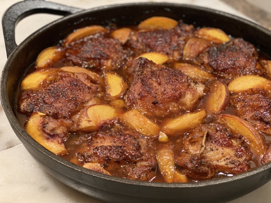 Barbeque peach chicken recipe baked in a cast-iron skillet with peach bbq sauce and fresh peaches. 