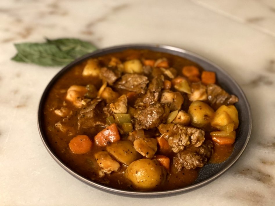 Coogan's chicken and beef stew served in a gray bowl on a white counter. 