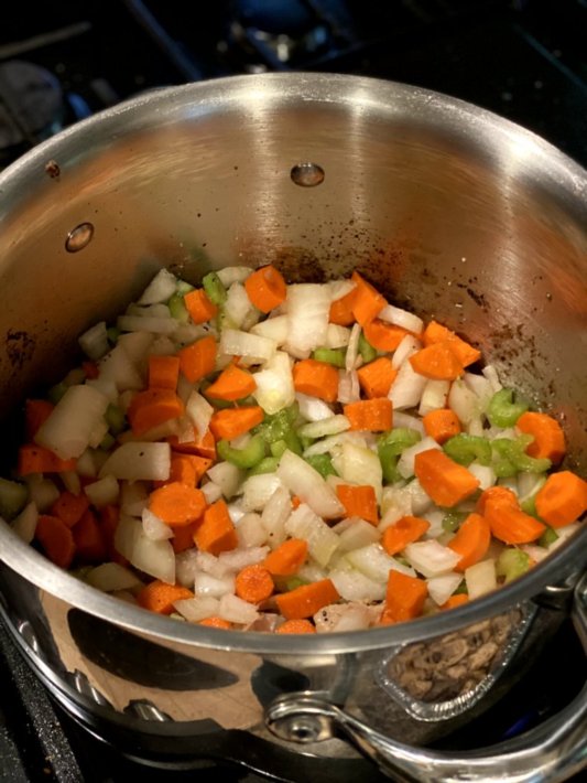 cooking the carrots, celery, and onions in a large pot to soften the veggies.