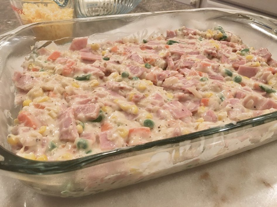 transfer the creamy mixture of vegetables and ham to the baking dish - ready for the oven. 