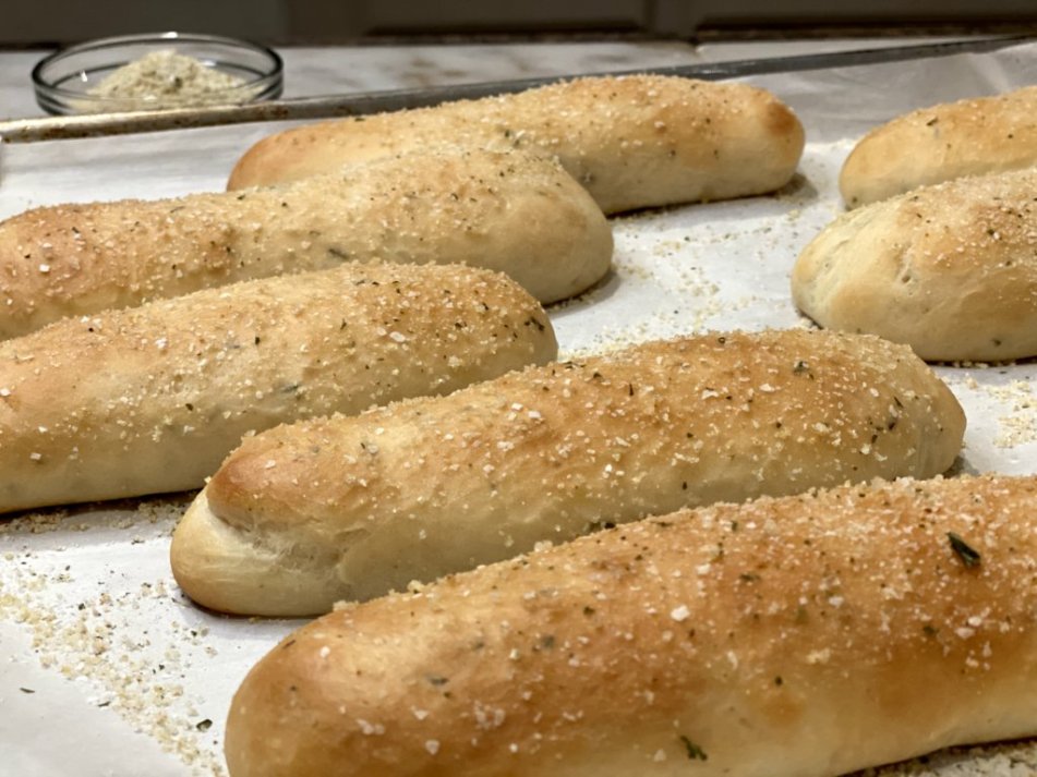 Italian buttery rosemary breadsticks on parchment paper with garlic