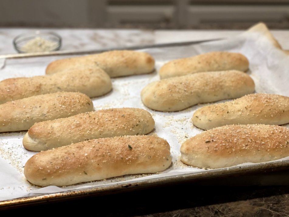 breadsticks made with rosemary sprigs baked on parchment paper with garlic salt sprinkled on top.