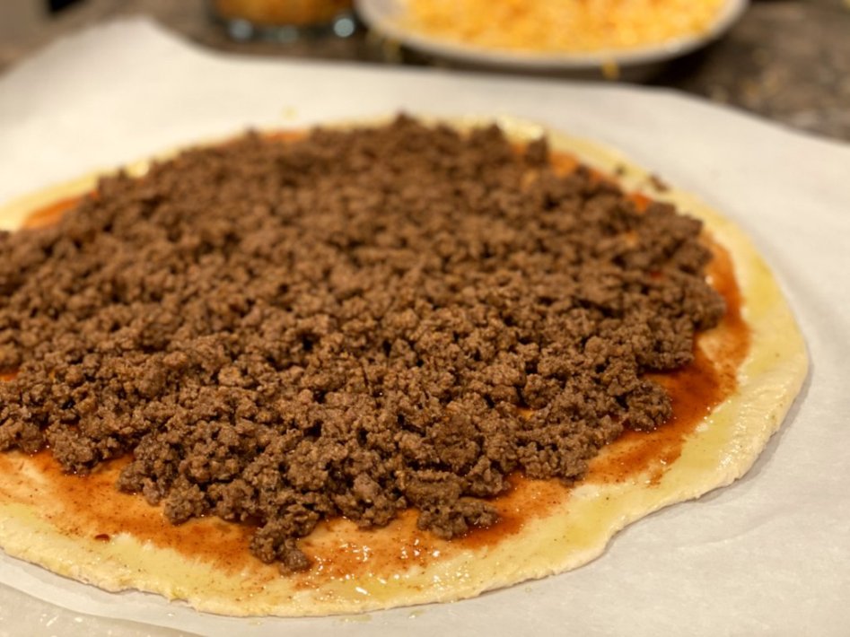 the taco meat mixture is then added to the pizza. 