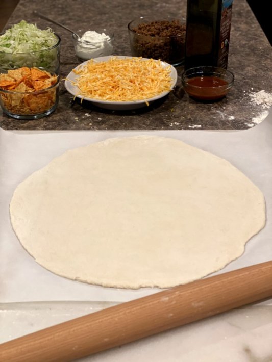 rolled out pizza dough ready for baking in the oven