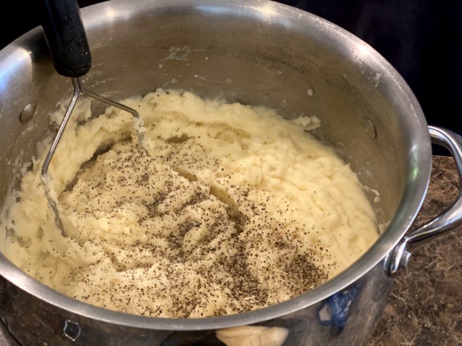 pepper added to mashed potatoes in a large pot
