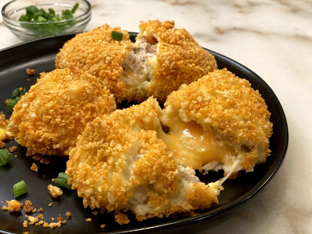 Cheesy Chicken Baked Croquettes on a black plate ready to eat. 