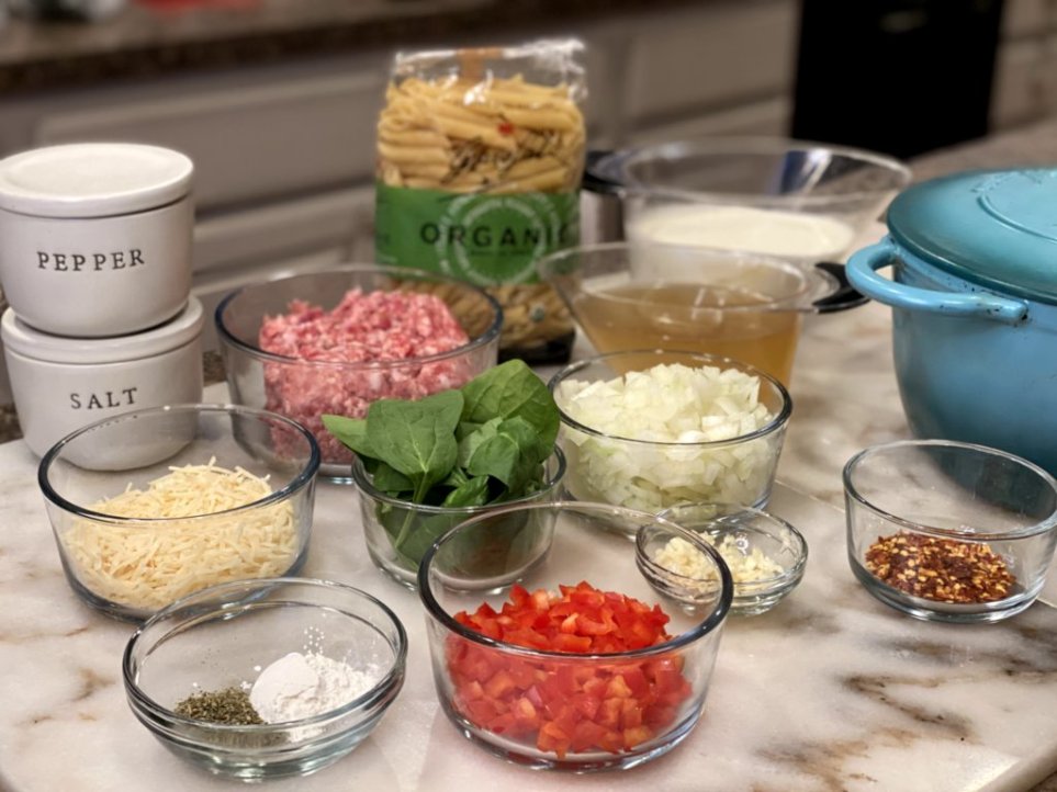 ingredients for creamy Italian sausage pasta recipe on a whilte marble counter. 