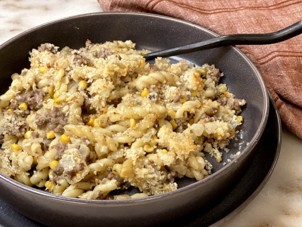 cooked ground beef with corn, sour cream, milk, cream of chicken soup and pasta noodles on the side served in a gray dish with a red napkin on the side