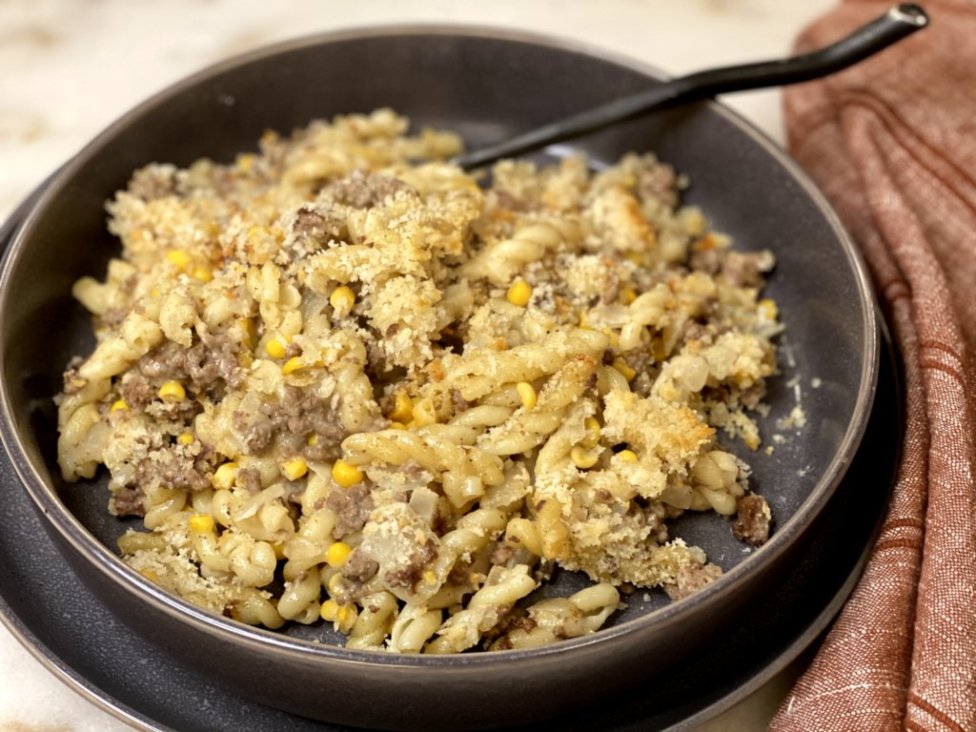 cooked ground beef with corn, sour cream, milk, cream of chicken soup and pasta noodles on the side served in a gray dish with a red napkin on the side