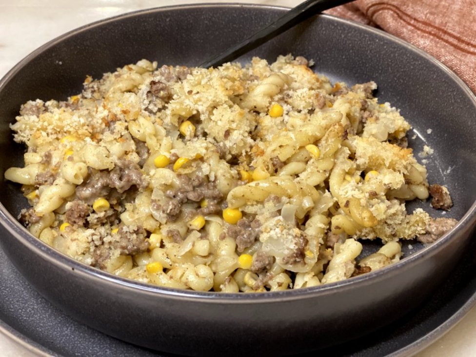 cooked ground beef with corn, sour cream, milk, cream of chicken soup and pasta noodles on the side served in a gray dish with a red napkin on the side