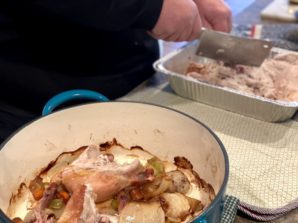 cutting up a roasted chicken to make homemade chicken broth, bone broth,  and homemade chicken stock