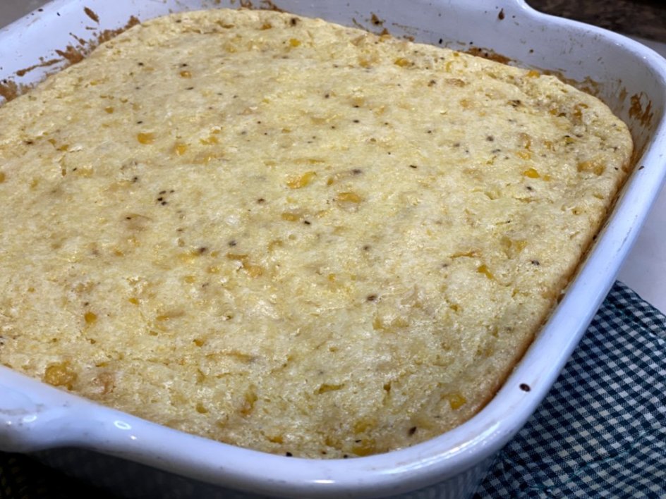 sweet corn casserole fresh out of the oven in a white baking dish