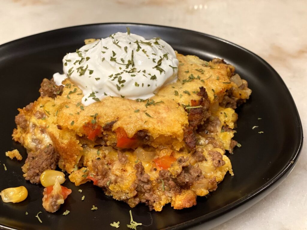 Sweet and Spicy Tamale Casserole  filled with ground beef, peppers, onions, corn muffin mix, and topped with sour cream