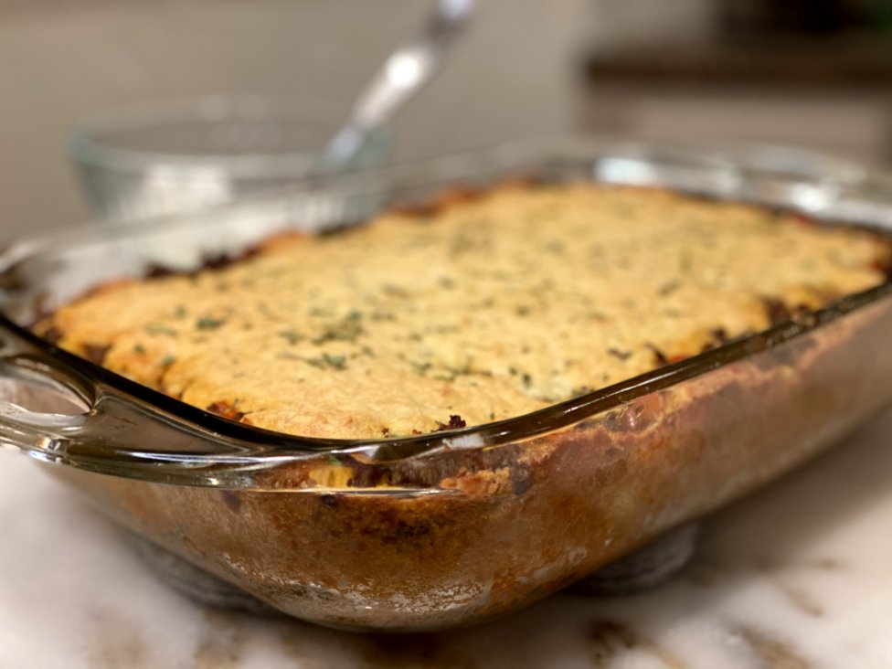 baked tamale casserole in a glass baking dish sprinkled with parsley