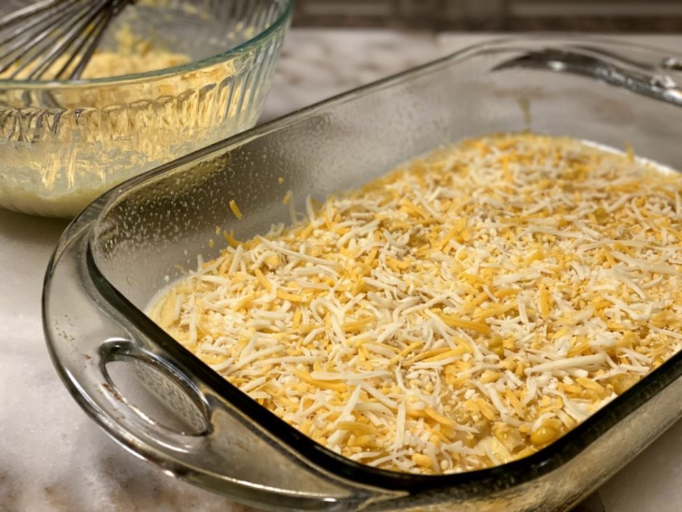 preparing a tamale casserole or tamale pie, topped with cheddar cheese. 