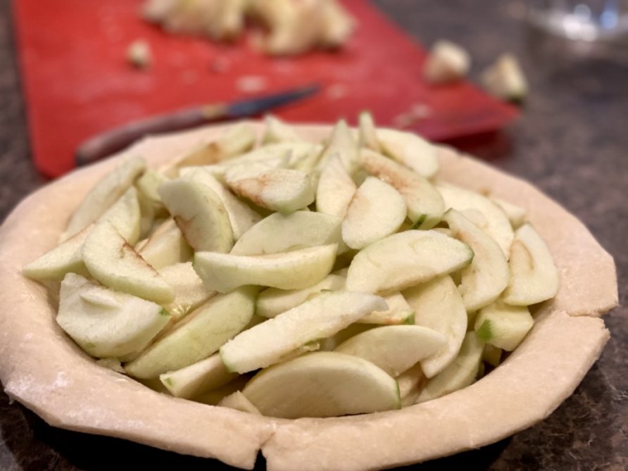 sliced Granny Smith apples in a pie crust, ready for baking. 