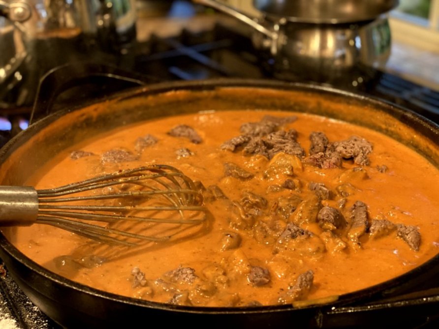 adding the browned steak bites into the stroganoff sauce