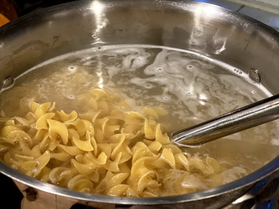 wide egg noodles pasta cooking in boiling water