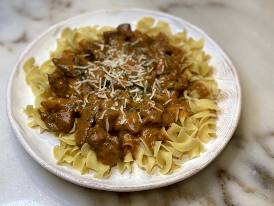 Steak stroganoff with noodles, grated parmesean and parsley
