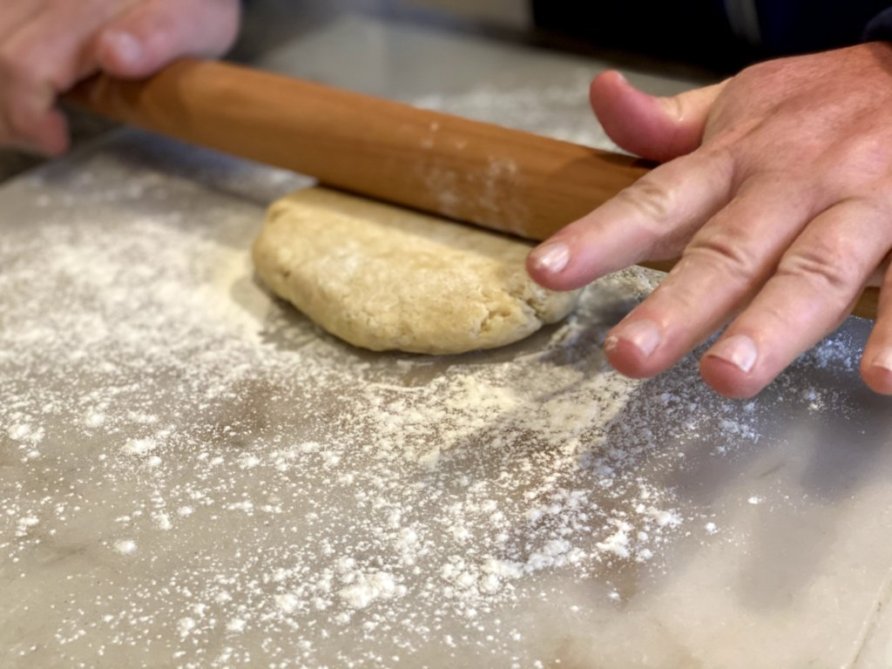 rolling out a butter pie crust dough with a wooden rolling pin. 