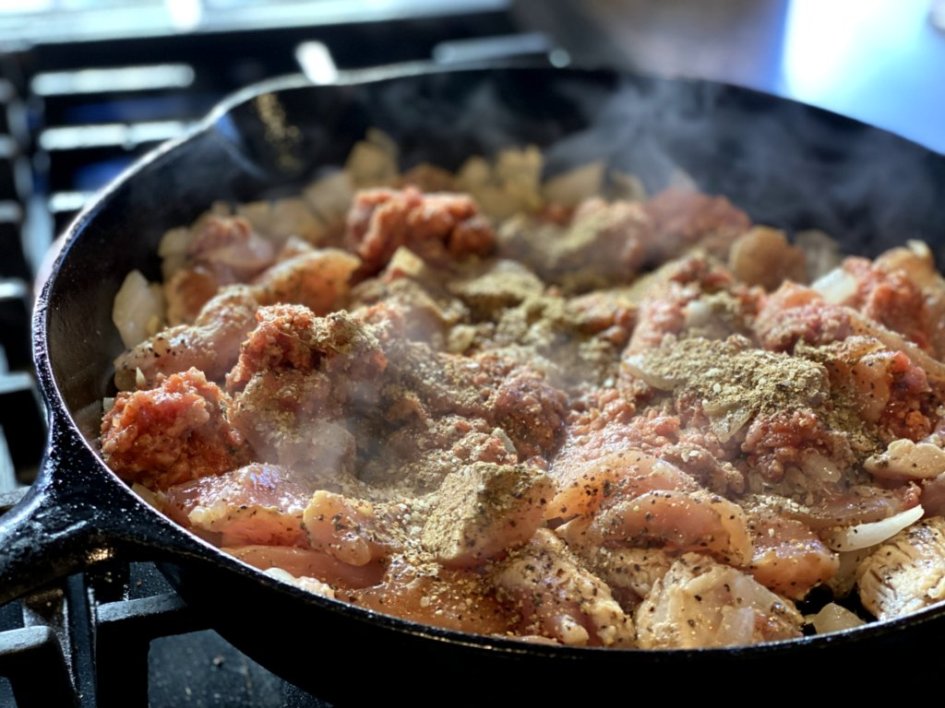 adding chicken breast meat and pork sausage and seasonings to the cast iron skillet