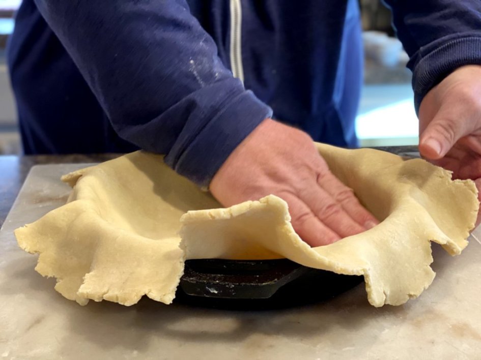 placing the crust into the bottom of a cast iron skillet