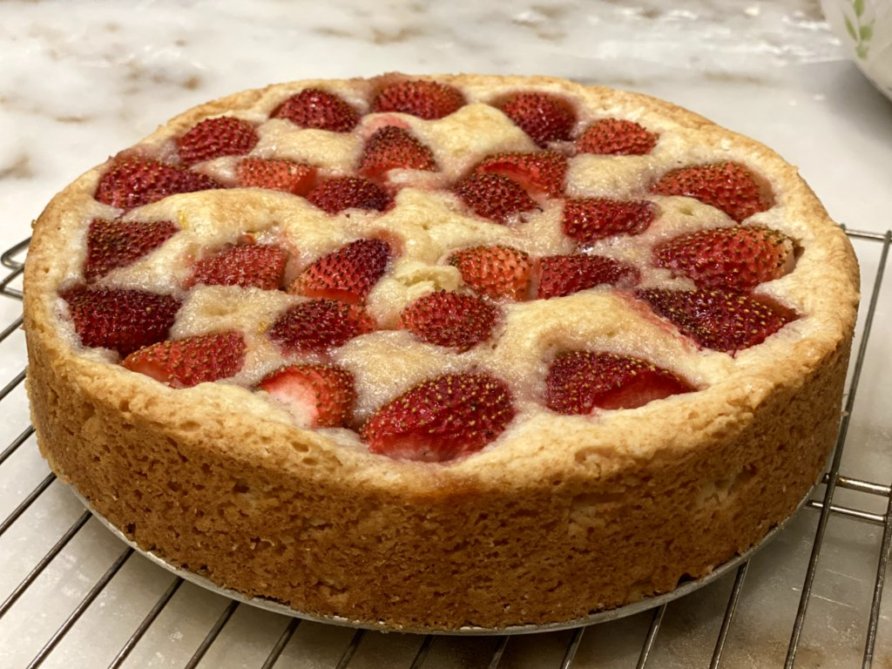 A strawberry cake cooling on a cooling rack. 