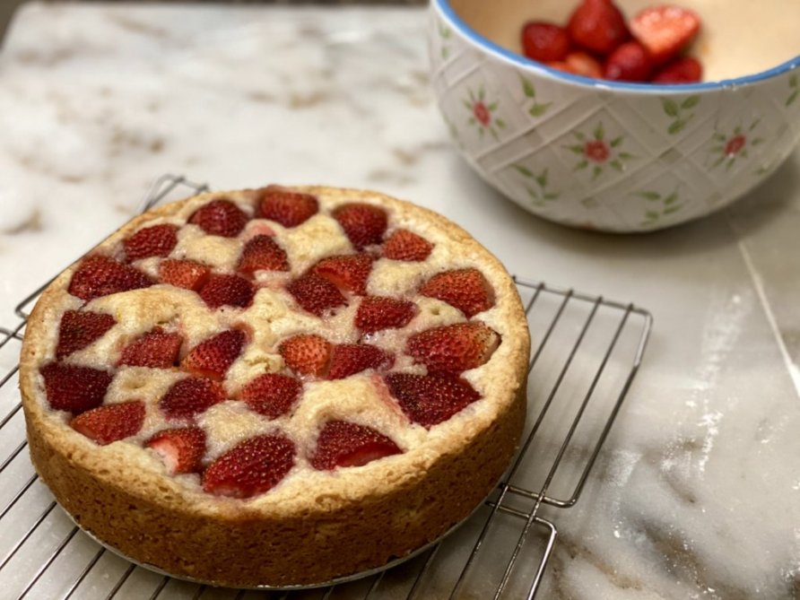 easy vanilla cake filled with strawberries with cut berries ready to be placed along the sides of the cake. 