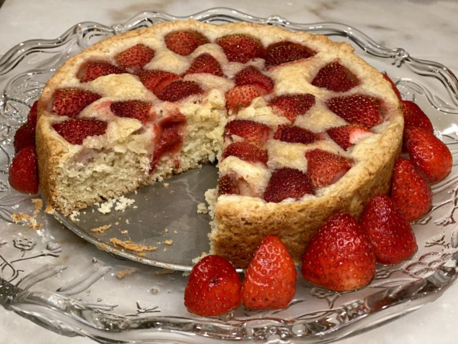 a sliced cake revealing the strawberries baked within and displayed along the outer edges. 
