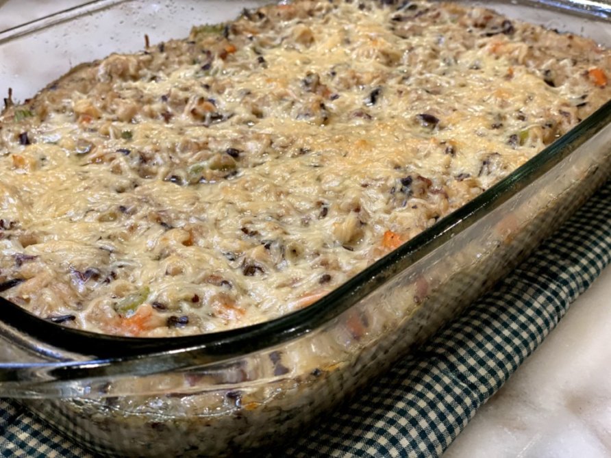 Wild Rice Chicken Casserole fresh out of the oven on a green and white checkered cloth. www.cooganskitchen.com
