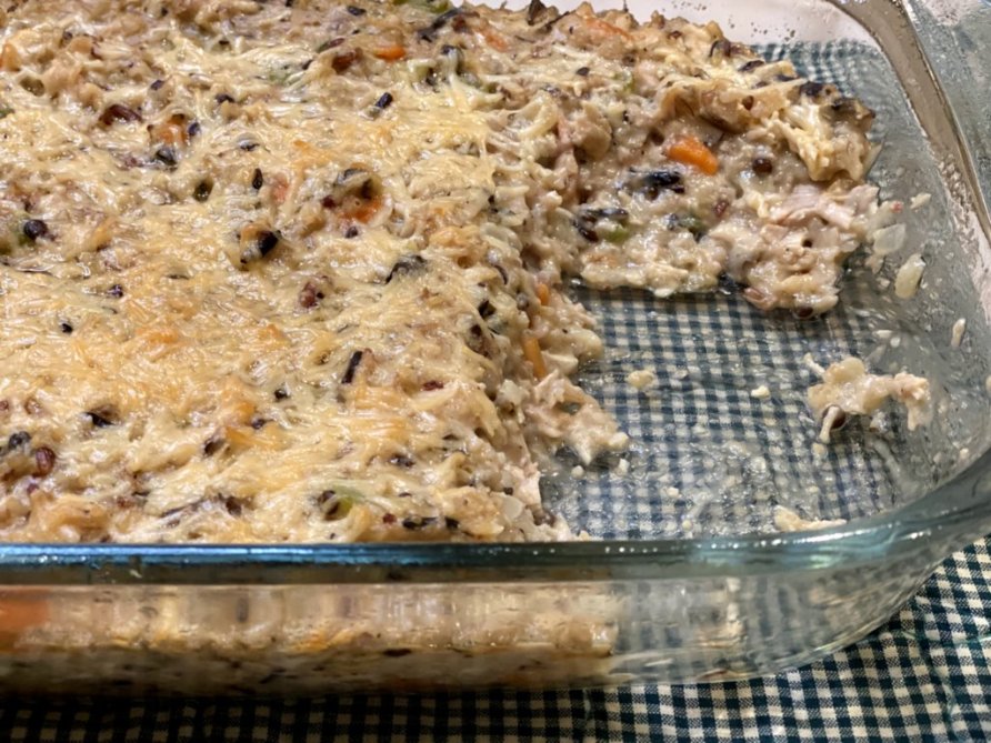 chicken and rice casserole with slices cut out of the glass casserole dish. 