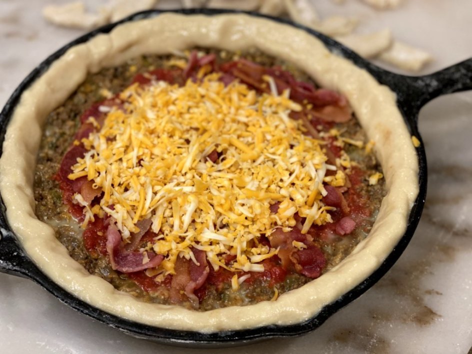adding shredded cheddar cheese to the topping of the cheeseburger pie