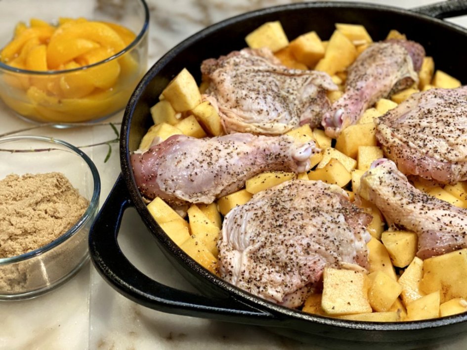 chicken pieces seasoned with salt and pepper added to a cast-iron skillet with squash and garlic. 
