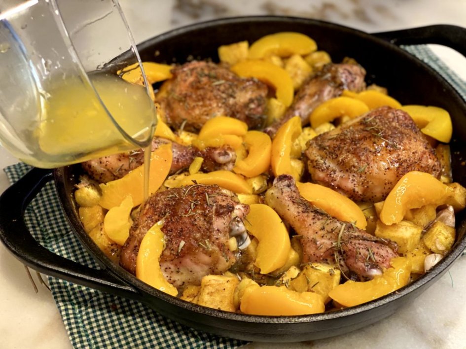 adding peaches and peach juice to the cast-iron skillet of chicken, squash, and garlic. 