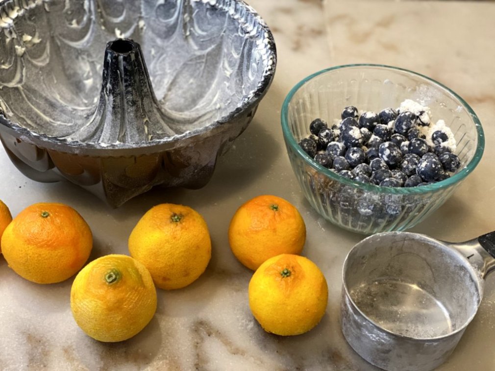 Bundt pan, a bowl of sugar coated blueberries, and oranges