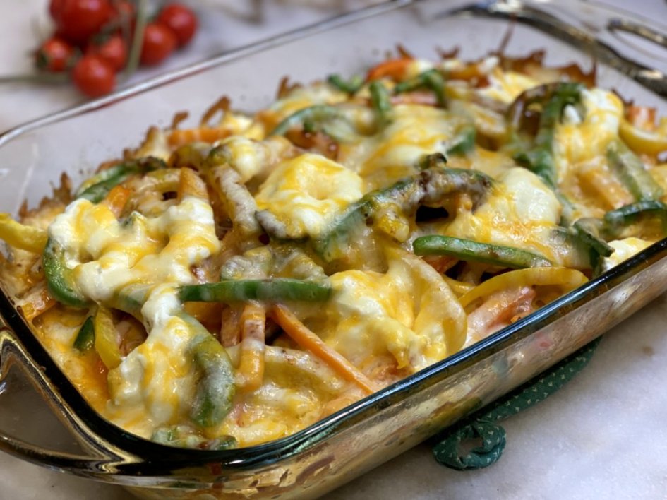 chicken fajita casserole with red bell peppers, green bell peppers, orange bell peppers, yellow bell peppers, jalapenos, sour cream and butter and covered in melted cheese