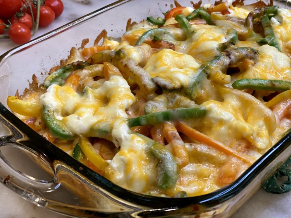 Chicken Fajita Casserole with tortillas in a glass baking dish with tomatoes on the side.