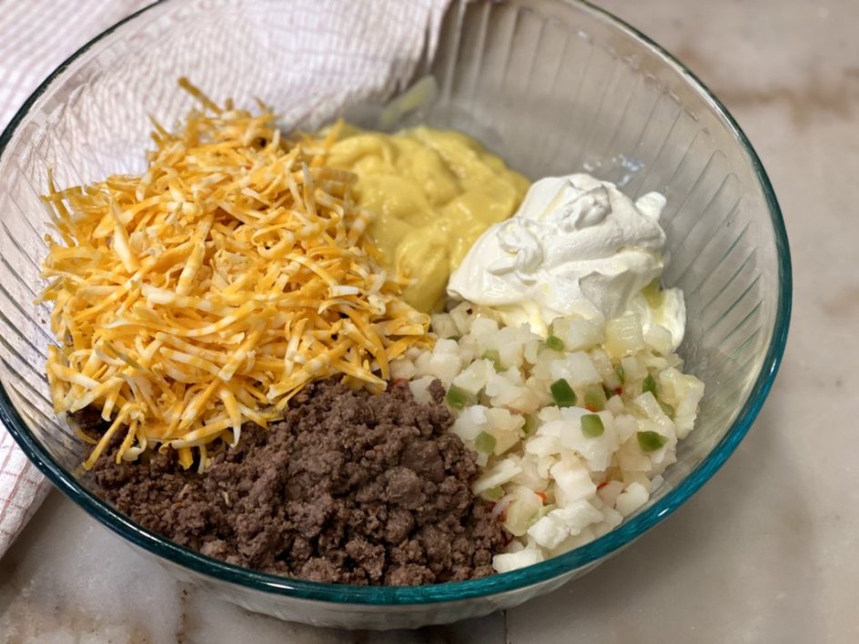 a bowl full of ingredients for hamburger hashbrown casserole - cheese, cream of chicken soup, sour cream, and ground beef