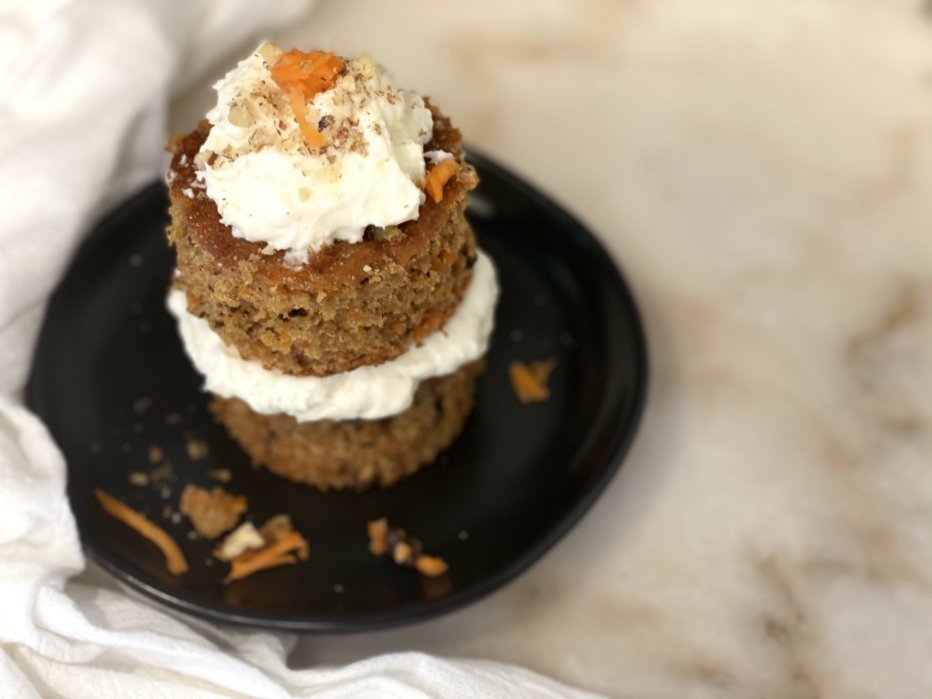 carrot cake muffins and cupcakes stacked on top of each other with frosting, nuts, and carrots. 