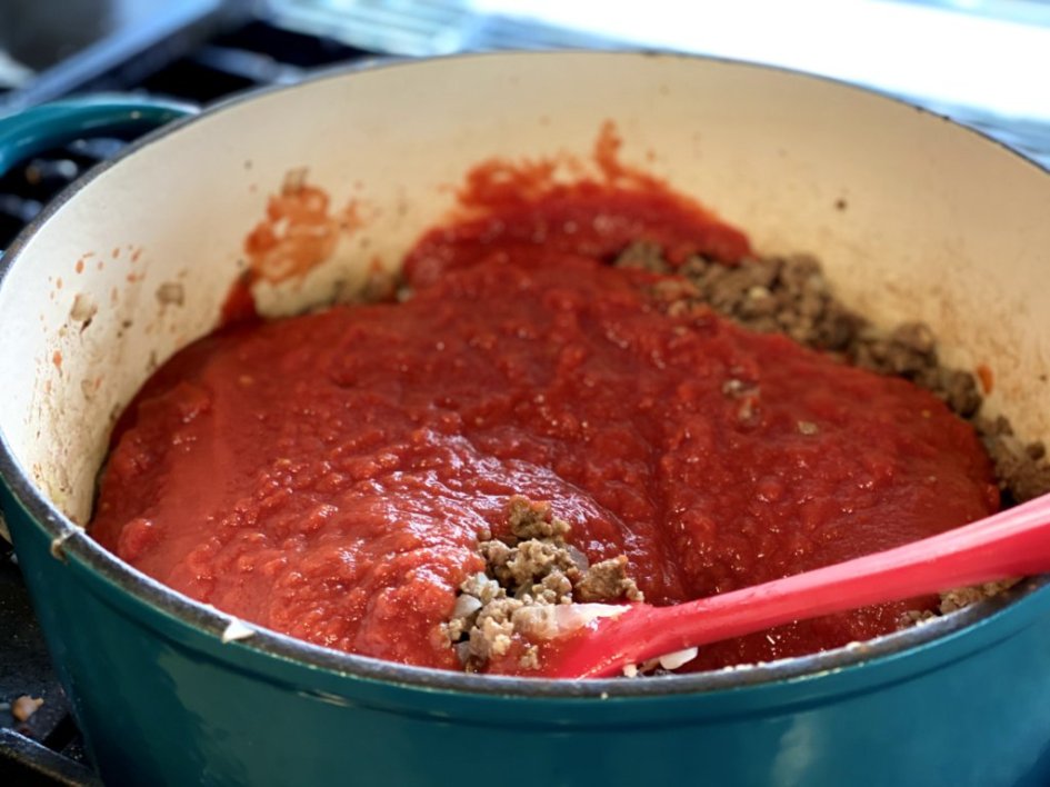 stirring in the tomatos and sauce to the cooked meat for the lasagna sauce
