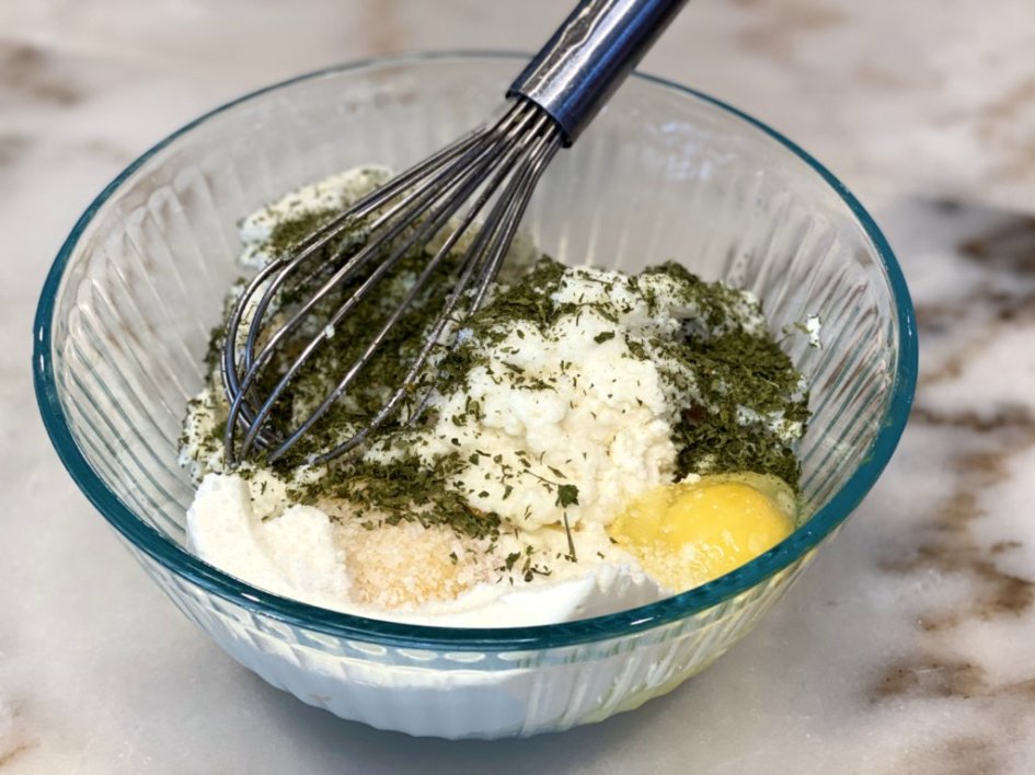 ricotta cheese mix in a glass bowl with a whisk