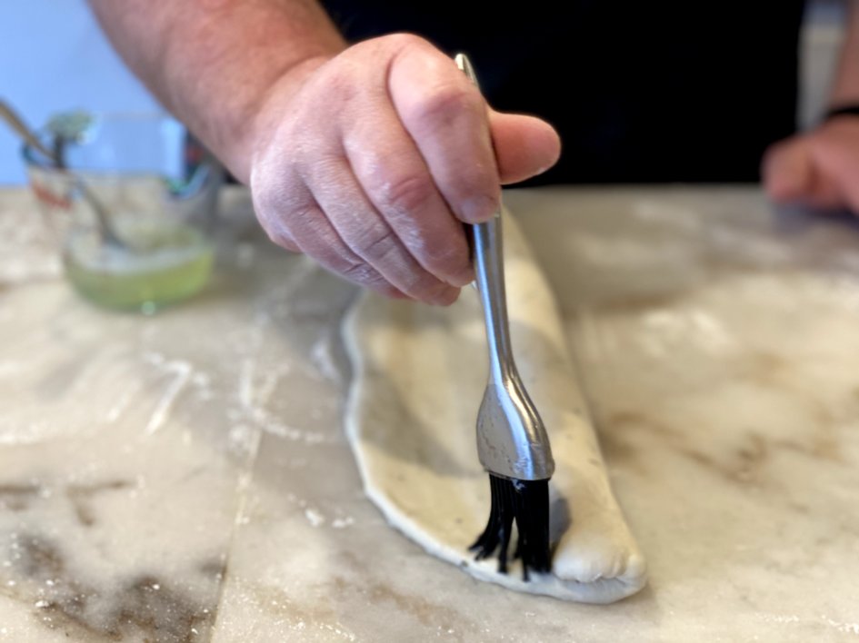 using an egg wash to wet the edges of the rolled up french bread dough