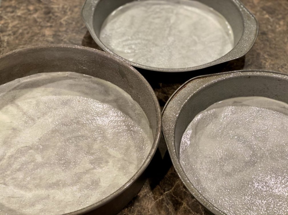 prepared cake pans with non-stick baking spray and parchment paper