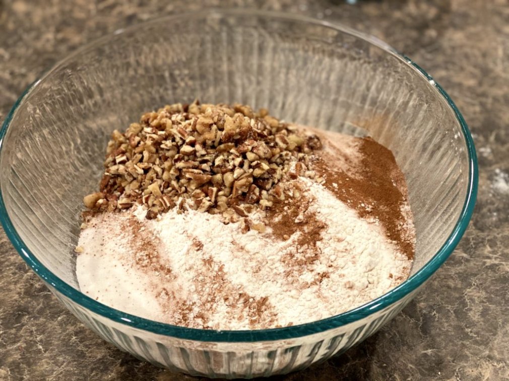 chopped pecans and walnuts added to the dry ingredients in a glass mixing bowl.
