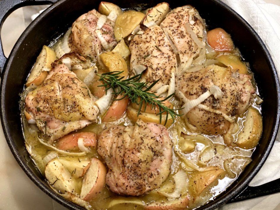 Baked Rosemary Chicken and Apples fresh out of the oven in a black cast-iron skillet.