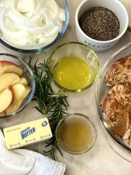 Ingredients needed to make this easy chicken dinner recipe. Chopped white onions, black pepper, olive oil, Honeycrisp apples, chicken thighs, rosemary sprigs, and butter. 