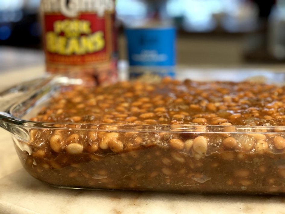 A side view of the calico bean casserole with cans of beans in the background. 